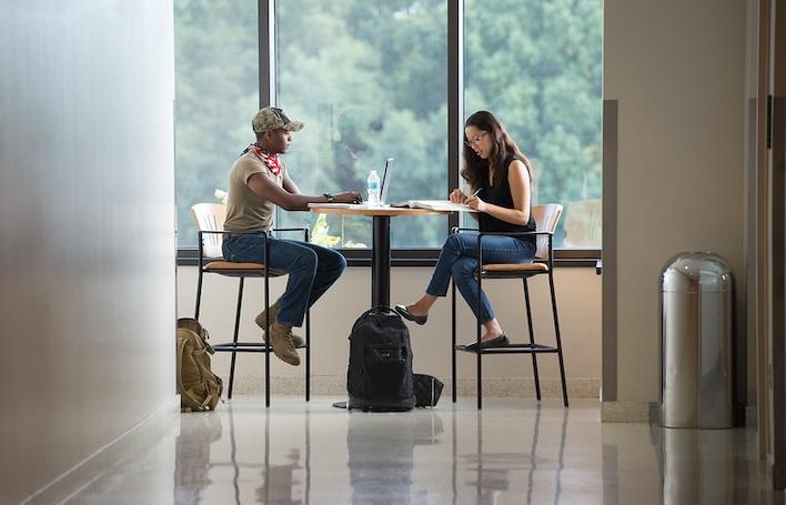 two students sitting at a table and studying